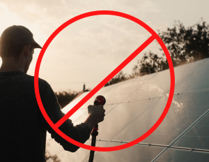a man using hose water on solar panels