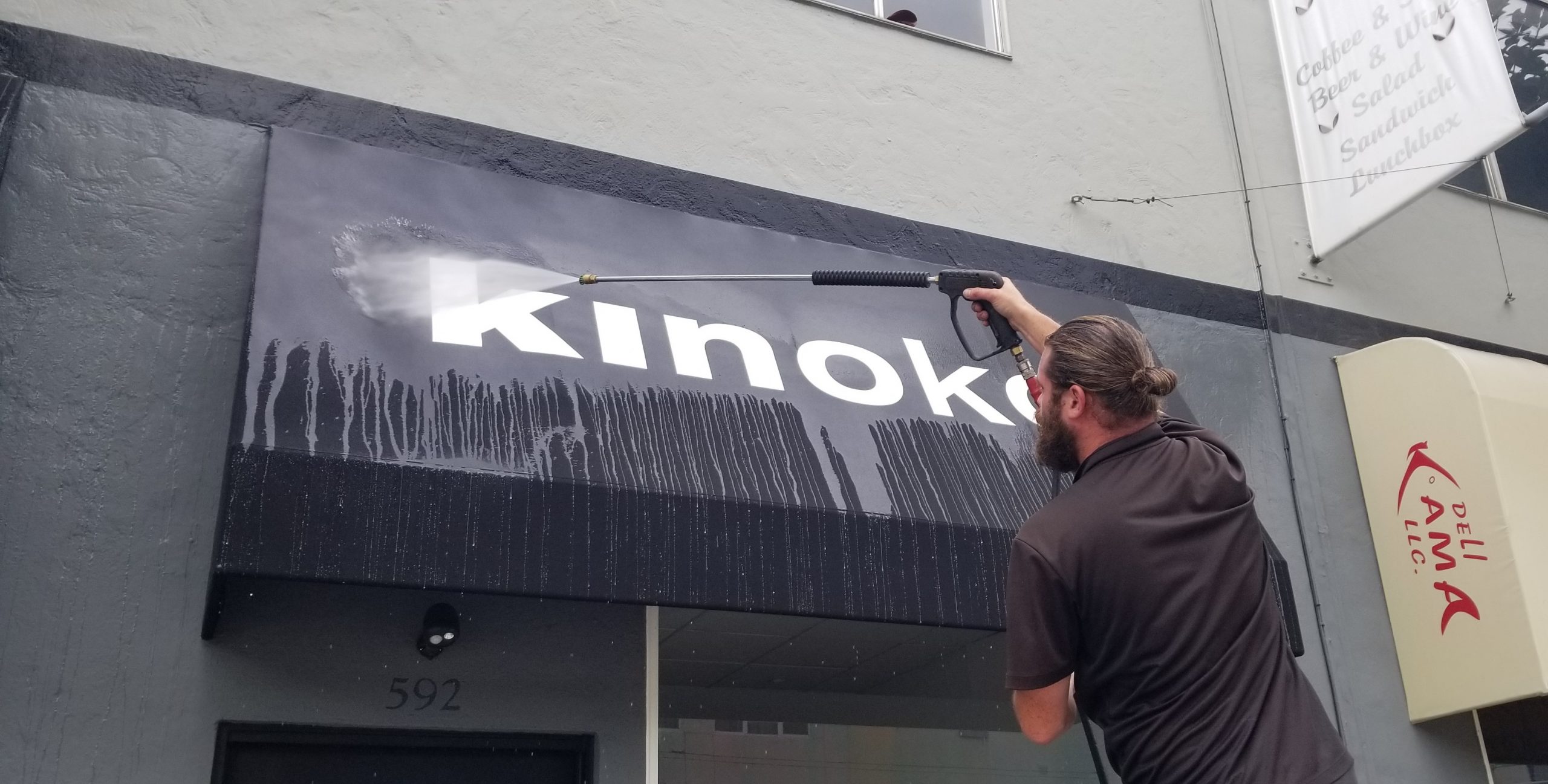 a man soft washing a commercial business storefront