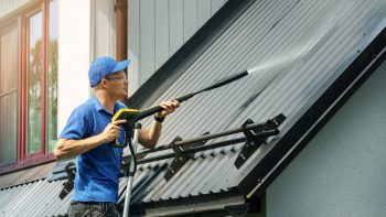 a professional using a better way of exterior cleaning for your roof, soft washing