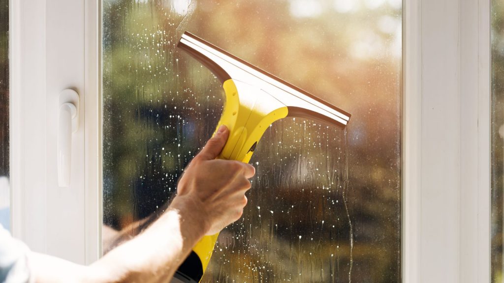 a commercial window cleaner using a squeegee on a window