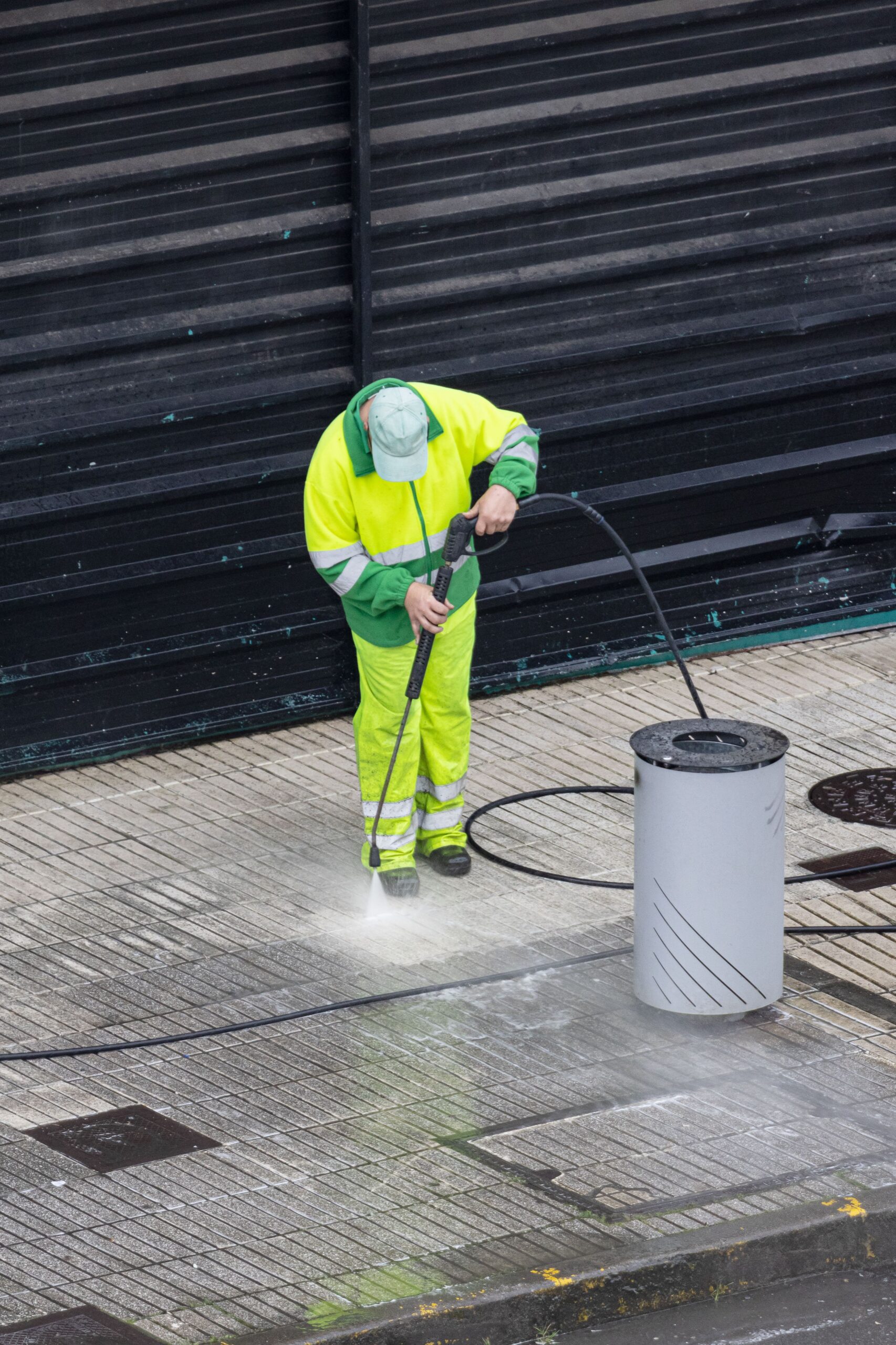 Worker cleaning a sidewalk with high pressure water jet machine. Copy space